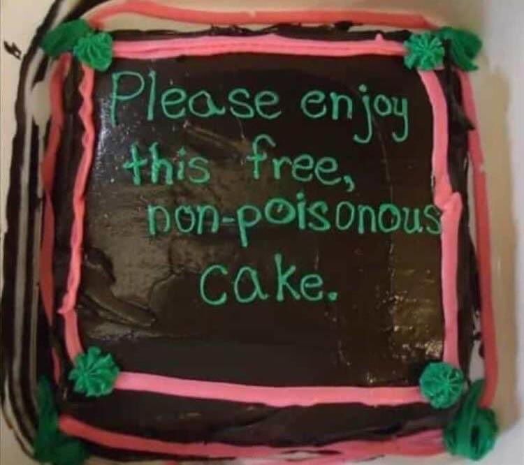 a cake with "please enjoy this free non-poisonous cake" written in green frosting on a black background